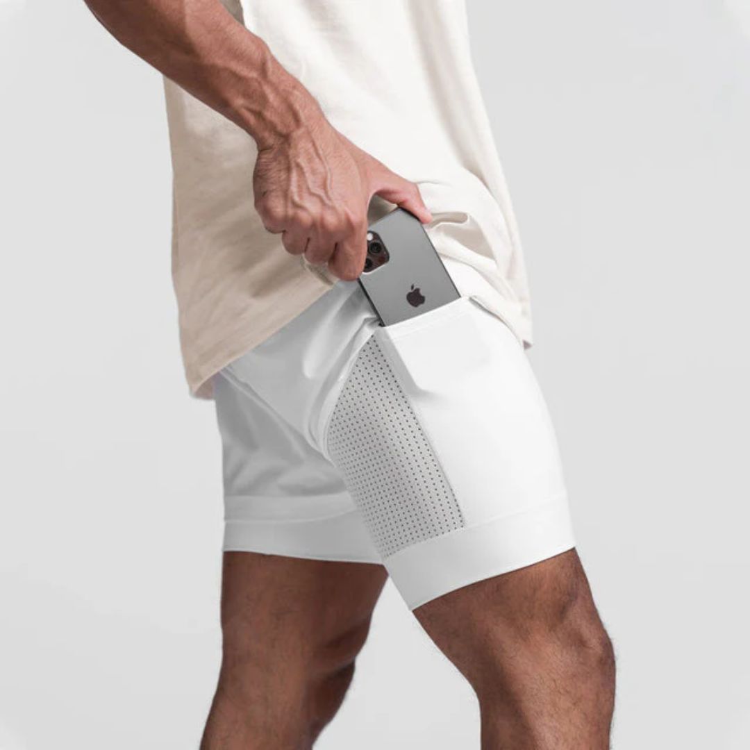 Mann in weißen Sportshorts mit Smartphone in der Tasche, Fitnessbekleidung, Herrenmode.