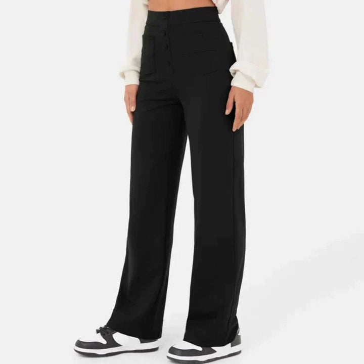 Frau trägt schwarze, weite Hose, hohe Taille, weiße Sneakers, modisch, lässig, Damenbekleidung.