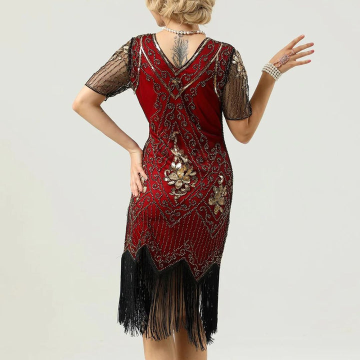 Frau in rotem, besticktem Charleston-Kleid mit Fransen und Perlenkette, Rückansicht.
