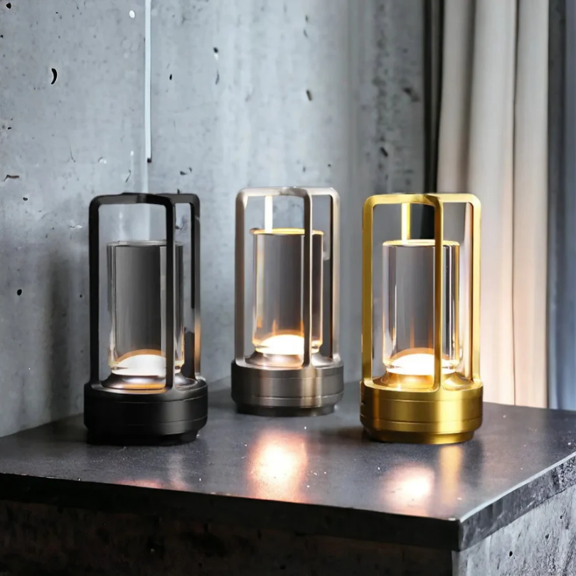 Drei moderne LED-Tischlampen in Schwarz, Silber und Gold auf Betonoberfläche.