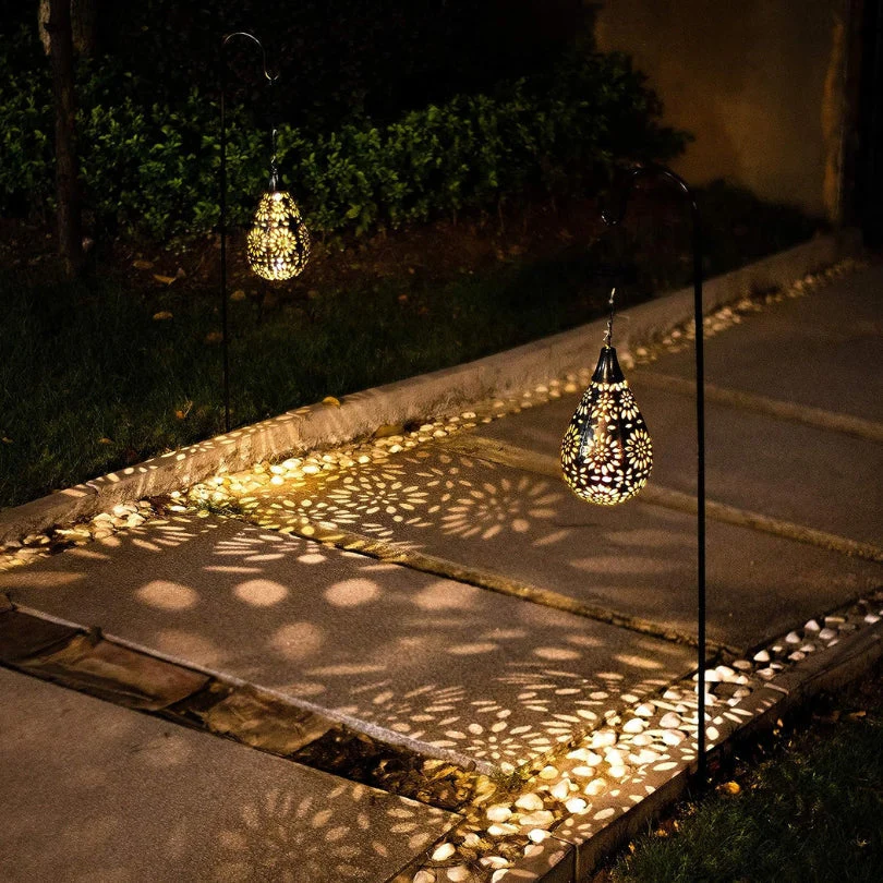 Solarbetriebene Gartenlaternen, tropfenförmig, schwarz, beleuchten Gehweg mit dekorativem Muster.