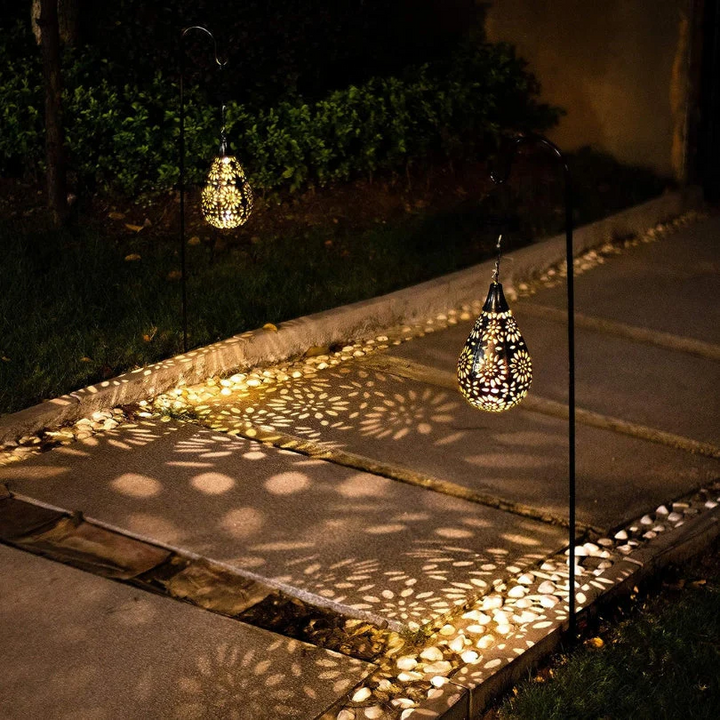 Solarbetriebene Gartenlaternen, tropfenförmig, schwarz, beleuchten Gehweg mit dekorativem Muster.