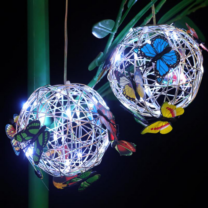 Zwei leuchtende LED-Lampions mit Schmetterlingsdekor, hängend, Nachtaufnahme.