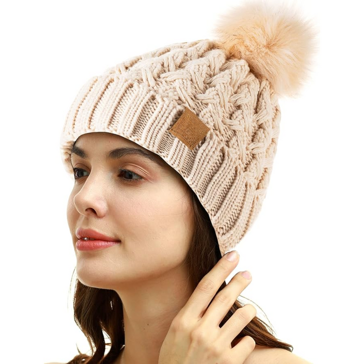 Frau mit beiger Strickmütze, Bommel, Wintermode, Damenaccessoire, warm, stilvoll, elegant.