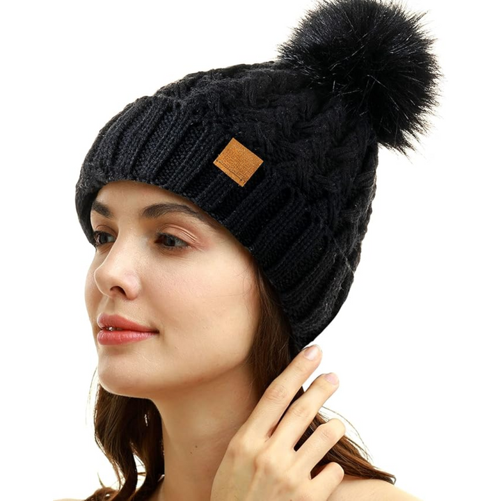 Frau mit schwarzer Strickmütze, Bommel, Wintermode, warm, stilvoll, Accessoire, Damenbekleidung.