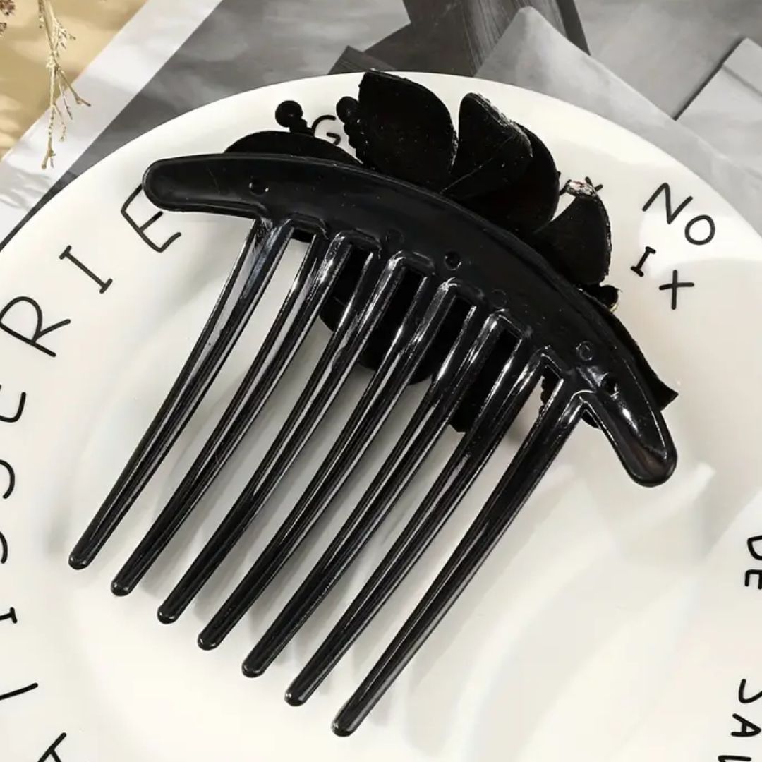 Schwarze Haarklammer aus Kunststoff auf weißem Teller, stilvolles Haaraccessoire.
