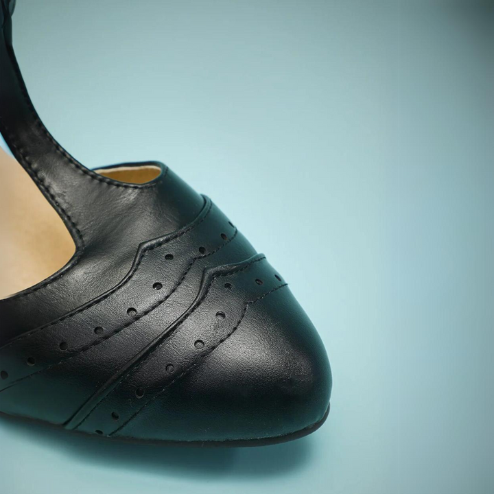 Schwarzer Lederschuh mit Lochmuster, elegantes Design, Damenmode, Nahaufnahme.