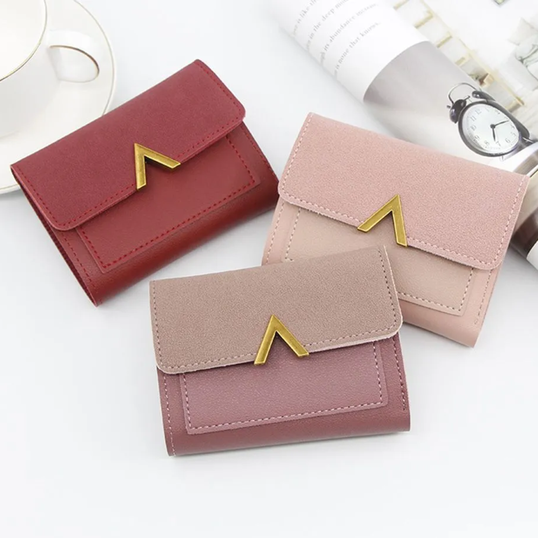 Drei Mini-Geldbörsen aus Samt und Leder in Rot, Rosa und Beige mit goldenen Verschlüssen.