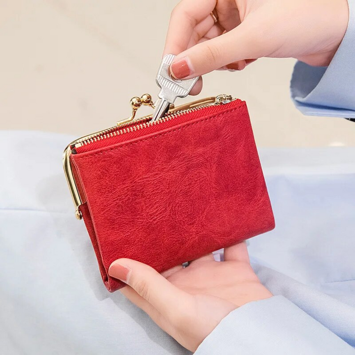 Rote Vintage-Kisslock-Geldbörse aus Leder, kompakt, mit Reißverschluss, in Hand gehalten.