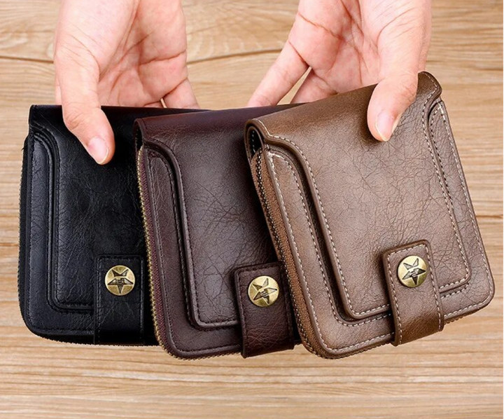 Drei Vintage-Leder-Geldbörsen in Schwarz, Braun und Hellbraun mit Sternknopf auf Holztisch.