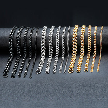 Verschiedene Edelstahl-Cuban-Link-Armbänder in Schwarz, Silber und Gold auf schwarzem Hintergrund.