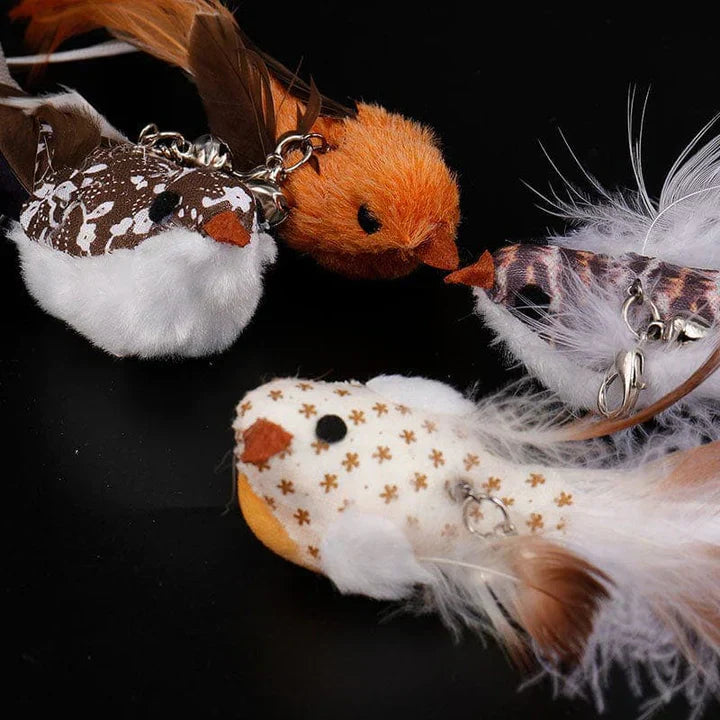 Vier bunte Stoffvögel mit Federn und Ketten auf schwarzem Hintergrund.