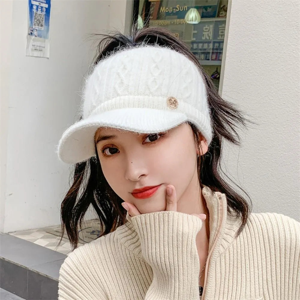Frau mit weißem Strick-Visor, modisches Accessoire, Wintermode, stilvoller Look.