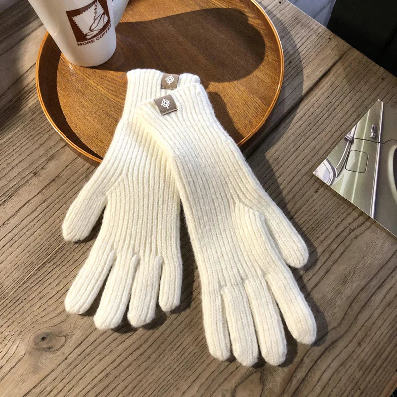 Weiße Strickhandschuhe aus Wolle auf Holztisch, stilvoll und warm für den Winter.