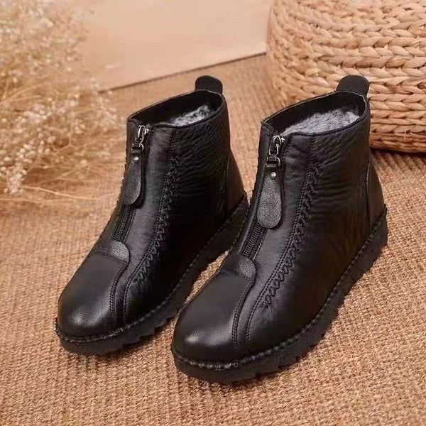 Schwarze, rutschfeste, warme Stiefeletten mit Reißverschluss auf Juteteppich.