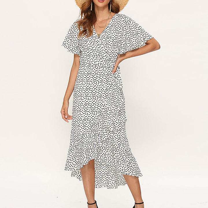 Frau in weißem gepunktetem Sommerkleid mit V-Ausschnitt und Strohhut, modisch, elegant.