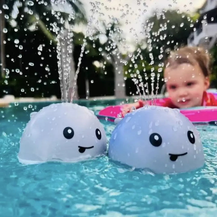 Zwei blaue Walspielzeuge im Pool mit spritzendem Wasser, Kind im Hintergrund.