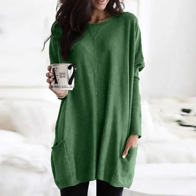 Frau in grünem Langarm-Tunika-Top mit Taschen, hält Tasse, lässige Damenmode.