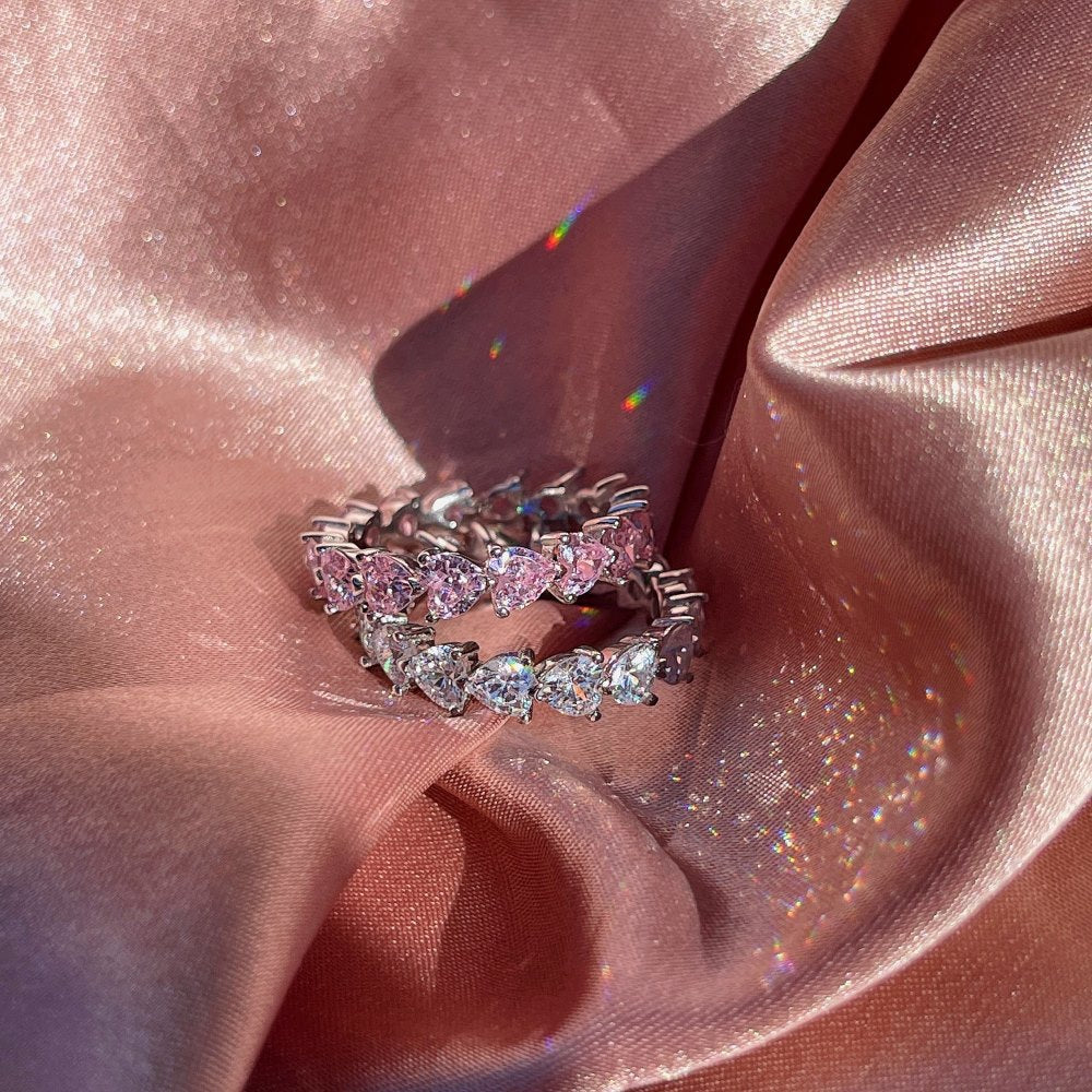 Silberring mit rosa Saphir, Herzform, auf schimmerndem Stoff, eleganter Schmuck, Hochzeitsring.