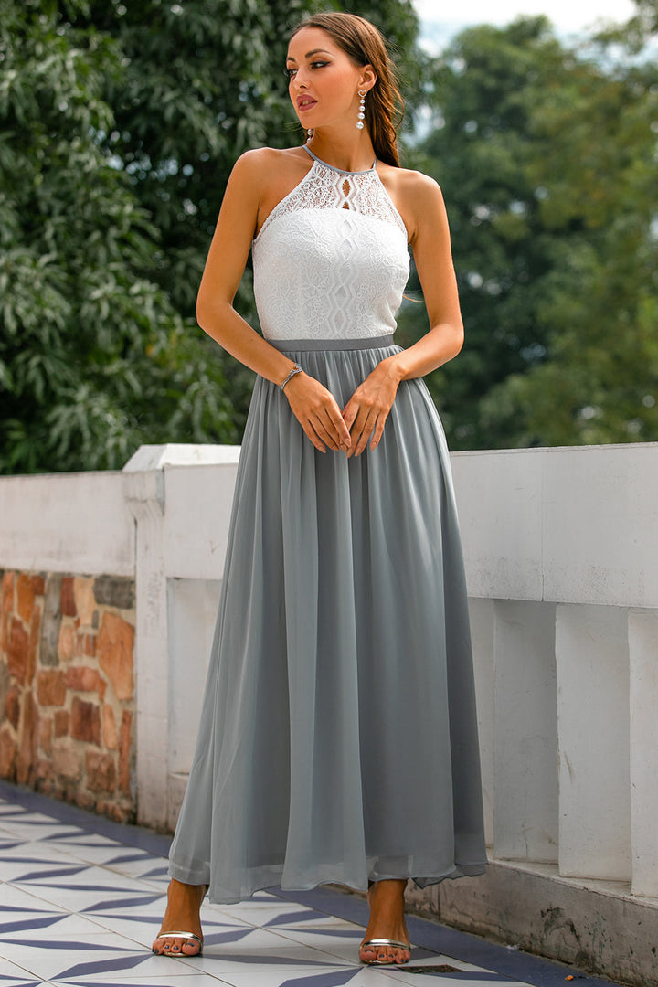 Frau im eleganten, ärmellosen Kleid mit weißem Spitzenoberteil und grauem Chiffonrock.