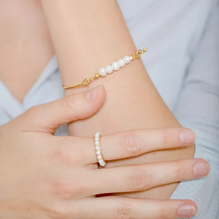 Goldenes Armband mit weißen Perlen, eleganter Schmuck, Damenmode, Hand, Nahaufnahme.