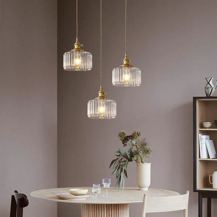 Drei hängende Glas-Pendelleuchten über rundem Esstisch, modernes Interieur, goldene Akzente.