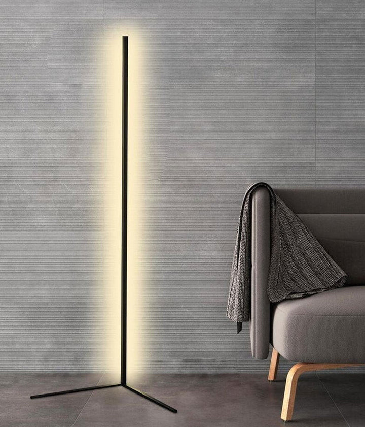 Lampa s dvěma rameny podstavce před šedou strukturovanou stěnou vedle křesla s přehozem 8