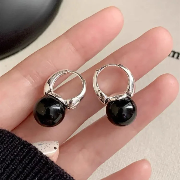 Silberne Ohrringe mit schwarzem Perlenanhänger, eleganter Schmuck, modisches Accessoire.