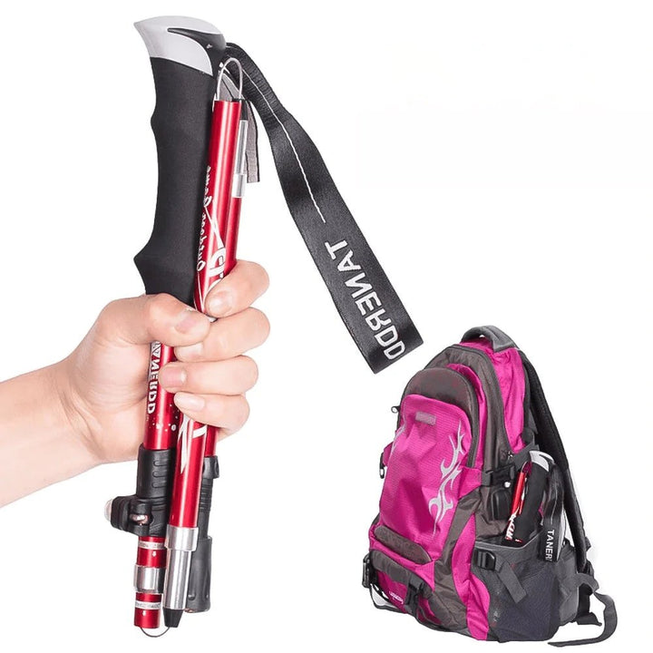 Faltbare, verstellbare Trekkingstöcke, rot, mit ergonomischem Griff, neben pinkem Rucksack.