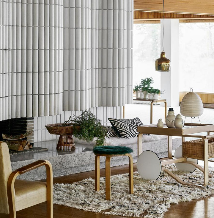 Moderne Wohnzimmerdekoration mit Akari Tischlampe, Holzstuhl, Teppich und Pflanzen.