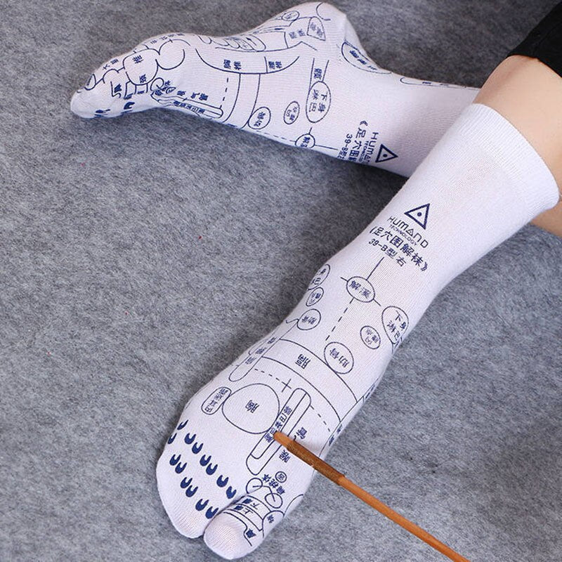 Weiße Akupressur-Socken mit blauen Reflexzonen-Diagrammen auf grauem Hintergrund.