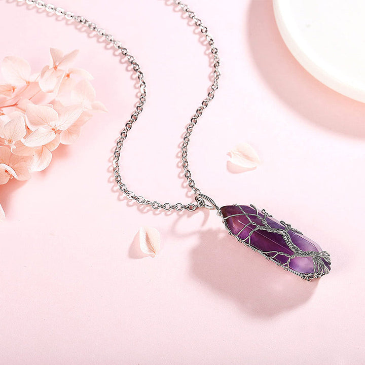 Silberkette mit lila Edelstein-Anhänger, filigranes Design, auf rosa Hintergrund.