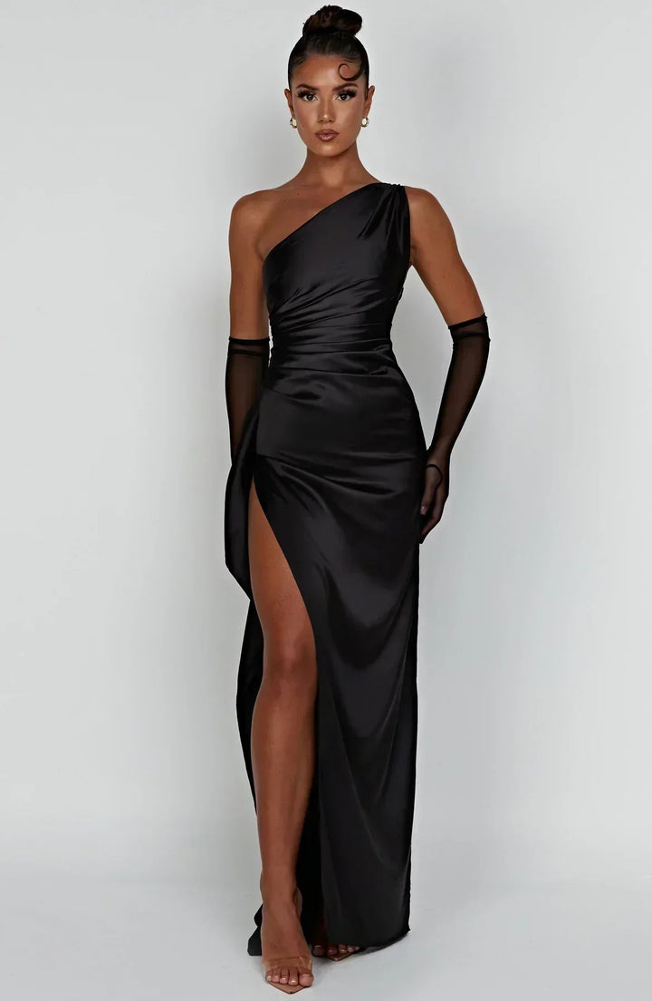 Frau in schwarzem, schulterfreiem Maxikleid mit hohem Schlitz und transparenten Handschuhen.