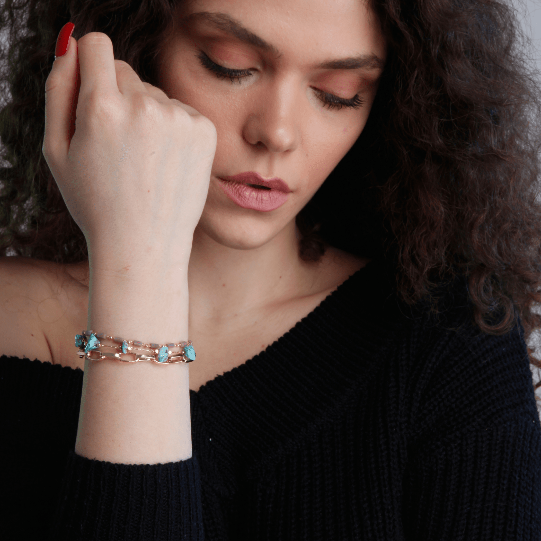 Frau mit elegantem Armband aus Roségold und blauen Edelsteinen, modisches Accessoire.