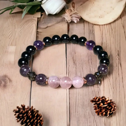 Armband aus Amethyst und Rosenquarz auf Holztisch, handgefertigter Schmuck, Natursteine.