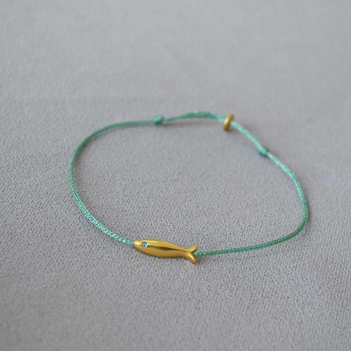 Grünes Armband mit gelbem Fischanhänger, minimalistisches Schmuckdesign, handgefertigt.