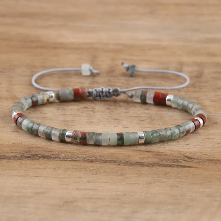 Armband aus Natursteinperlen, grün und rot, verstellbar, handgefertigt, auf Holzoberfläche.