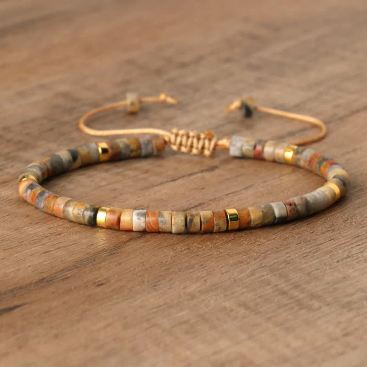 Armband aus Natursteinperlen, verstellbar, beige und gold, handgefertigt, auf Holzoberfläche.