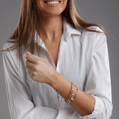 Frau mit weißer Bluse trägt elegante Armbänder aus Gold und Silber, Schmuckmode Accessoire.