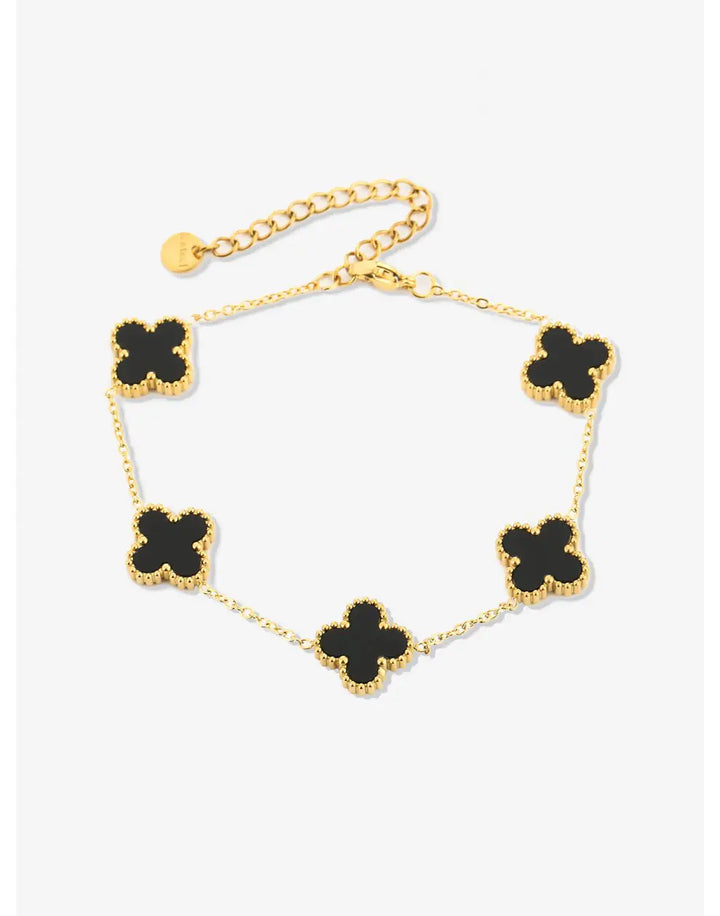 Goldenes Armband mit schwarzen Kleeblatt-Anhängern, elegantes Schmuckdesign, Damenaccessoire.