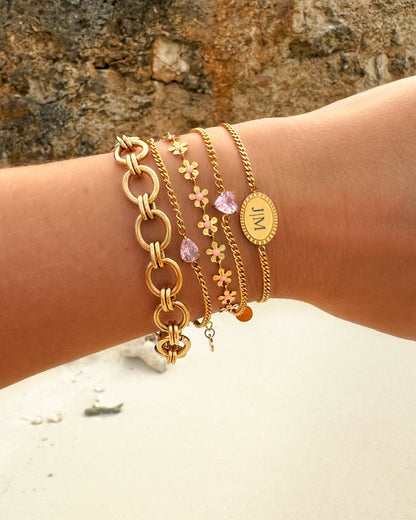 Goldene und rosa Armbänder-Set, Damenmode, Schmuck, Blumenmuster, Strandhintergrund.
