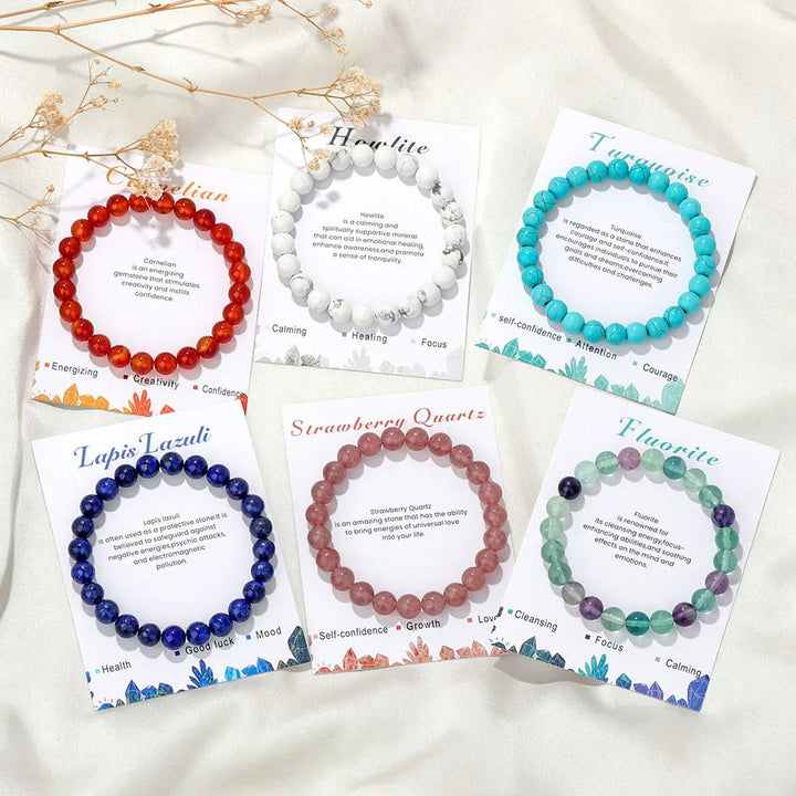 Sechs Edelstein-Armbänder auf Karten: Karneol, Howlith, Türkis, Lapislazuli, Rosenquarz, Fluorit.