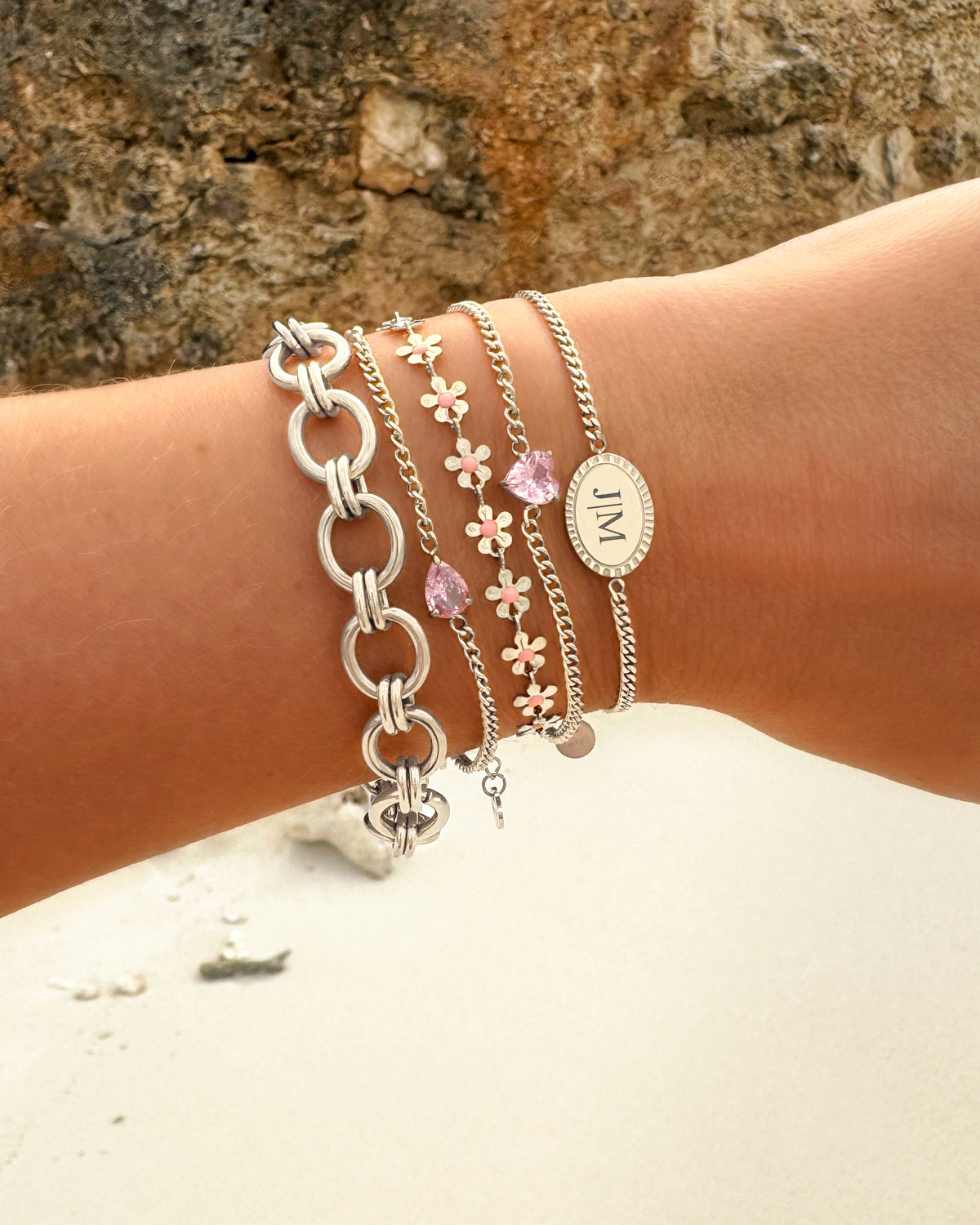 Silberne und rosa Armbänder-Set am Handgelenk, modische Schmuckaccessoires.