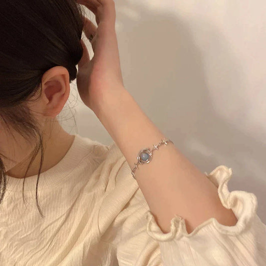 Frau mit silbernem Armband, Perlenanhänger, elegantes Design, modisches Accessoire.