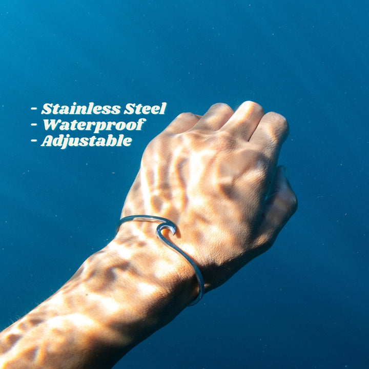 Hand mit Edelstahlarmband, wasserdicht, verstellbar, unter Wasser, blaues Hintergrund.