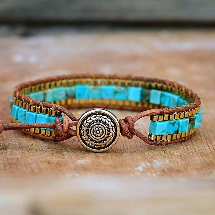 Braunes Lederarmband mit türkisfarbenen Steinen und goldener Verzierung, handgefertigt.