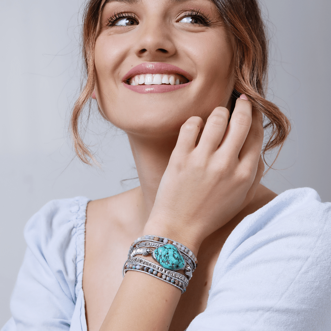 Frau mit türkisfarbenem Armband, Silberdetails, lächelnd, modisches Accessoire, Nahaufnahme.