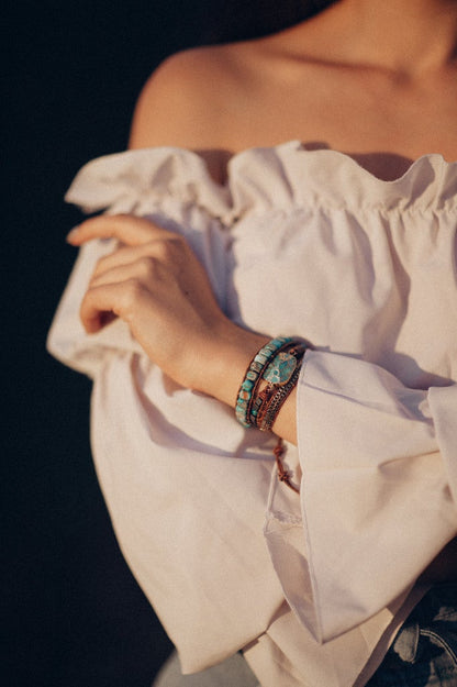 Frau mit weißer Bluse trägt türkisfarbenes Armband, Boho-Stil, handgefertigter Schmuck.