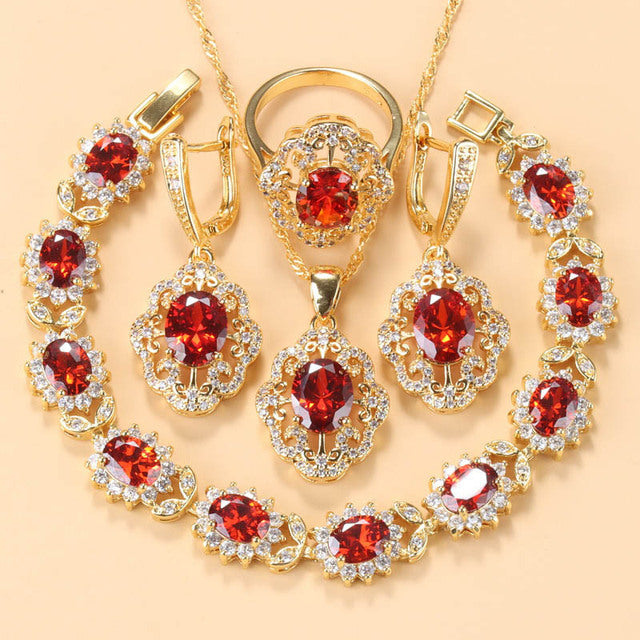 Goldene Schmuckset mit roten Zirkonia, bestehend aus Armband, Ring, Ohrringen und Halskette.