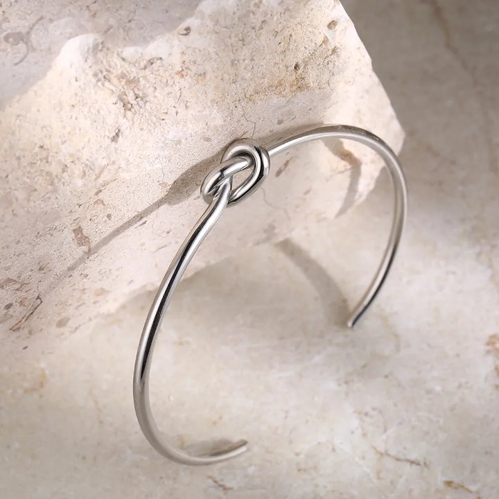 Silberarmreif mit Knoten-Design auf Stein, minimalistischer Schmuck, elegantes Accessoire.